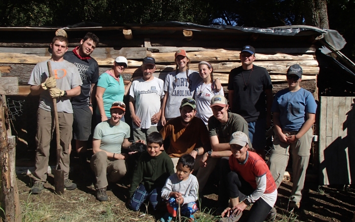 A group of people pose for a photo in front of large pieces of wood. 